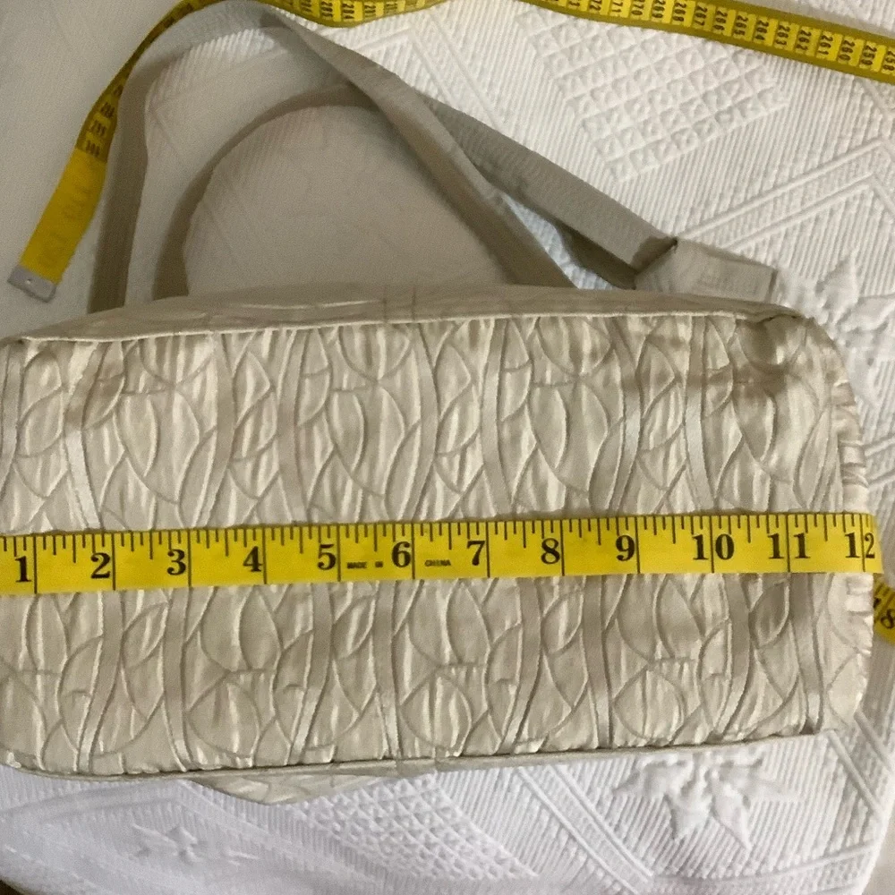 FABRIC SHOULDER BAG WITH OUTSIDE SURROUNDING POCKETS IN A CREAM AND TAUPE COLOR.